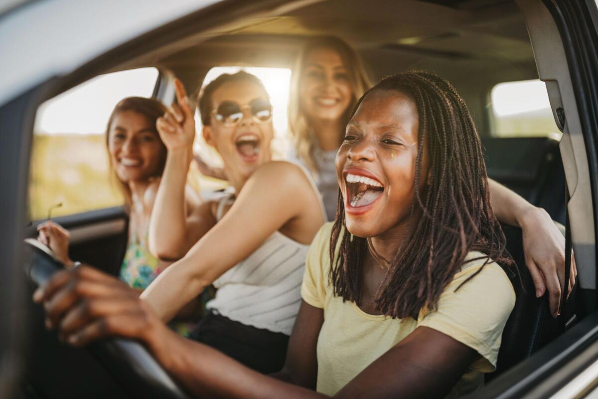 Four students laughing together in the back seat of a car on a shared ride